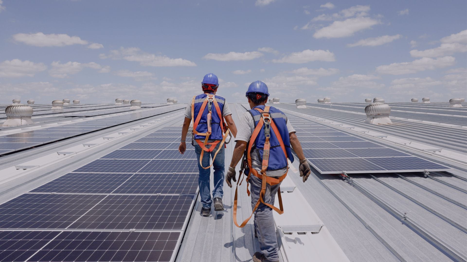 Male workers on a roof covered with solar panels