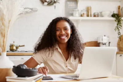 Woman smiling at camera while working on her laptop