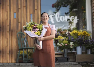 Woman holding flowers outside of flower shop