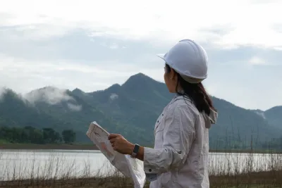 An engineer looking at the mountains while holding a plan