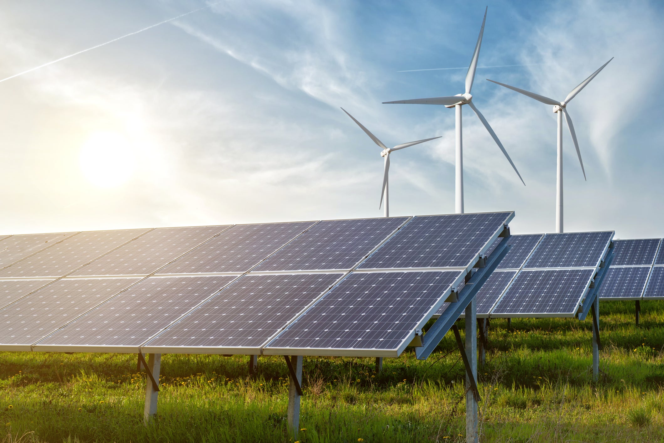Climate finance at scale: Image of solar panels in a green field with wind turbines in the background against a blue sky. FinDev Canada logo in the bottom left.