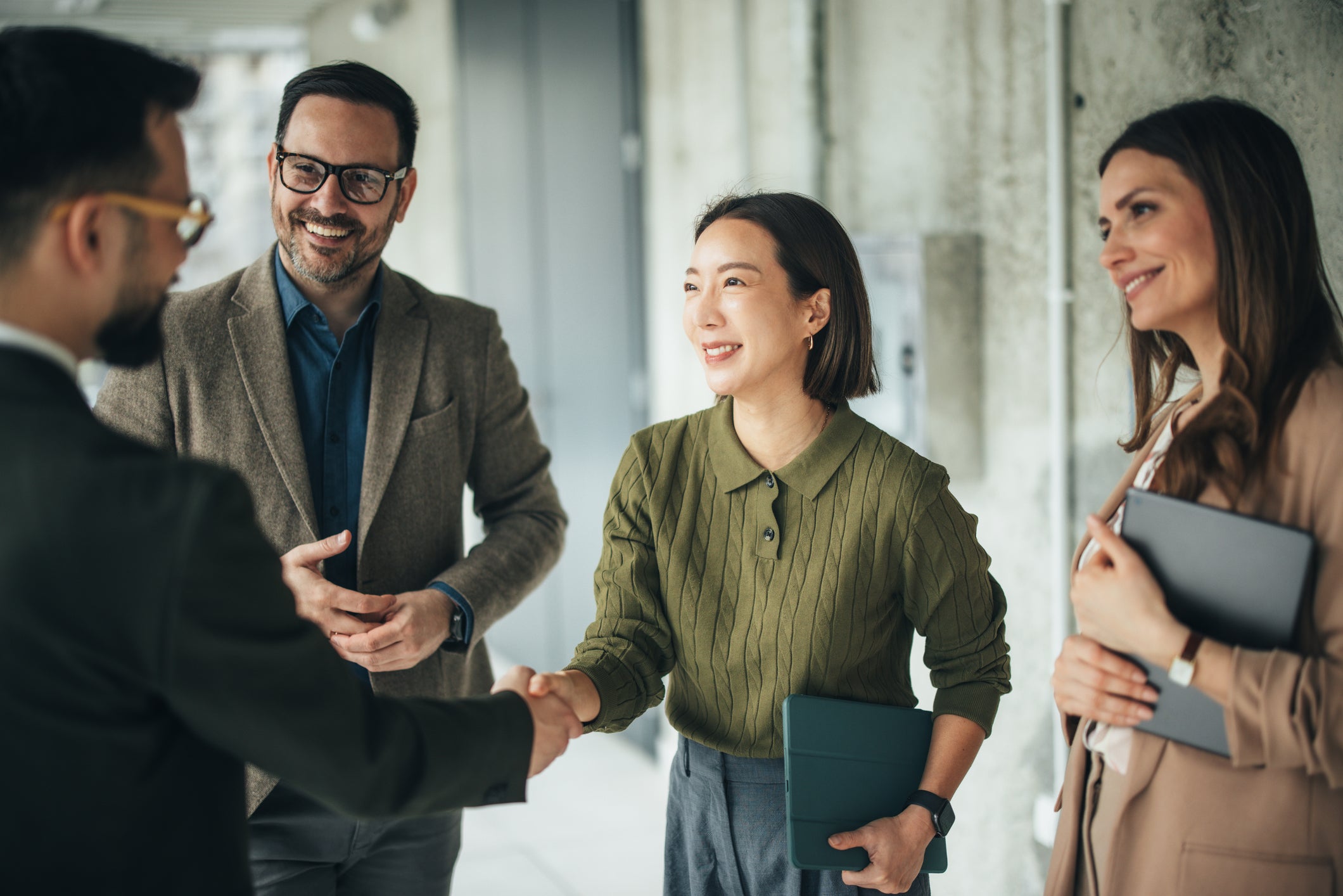 Partnerships for increased impact: Image of a woman shaking hands with a man. Two other individuals stand to the left and right of the woman. FinDev Canada logo in the bottom left.