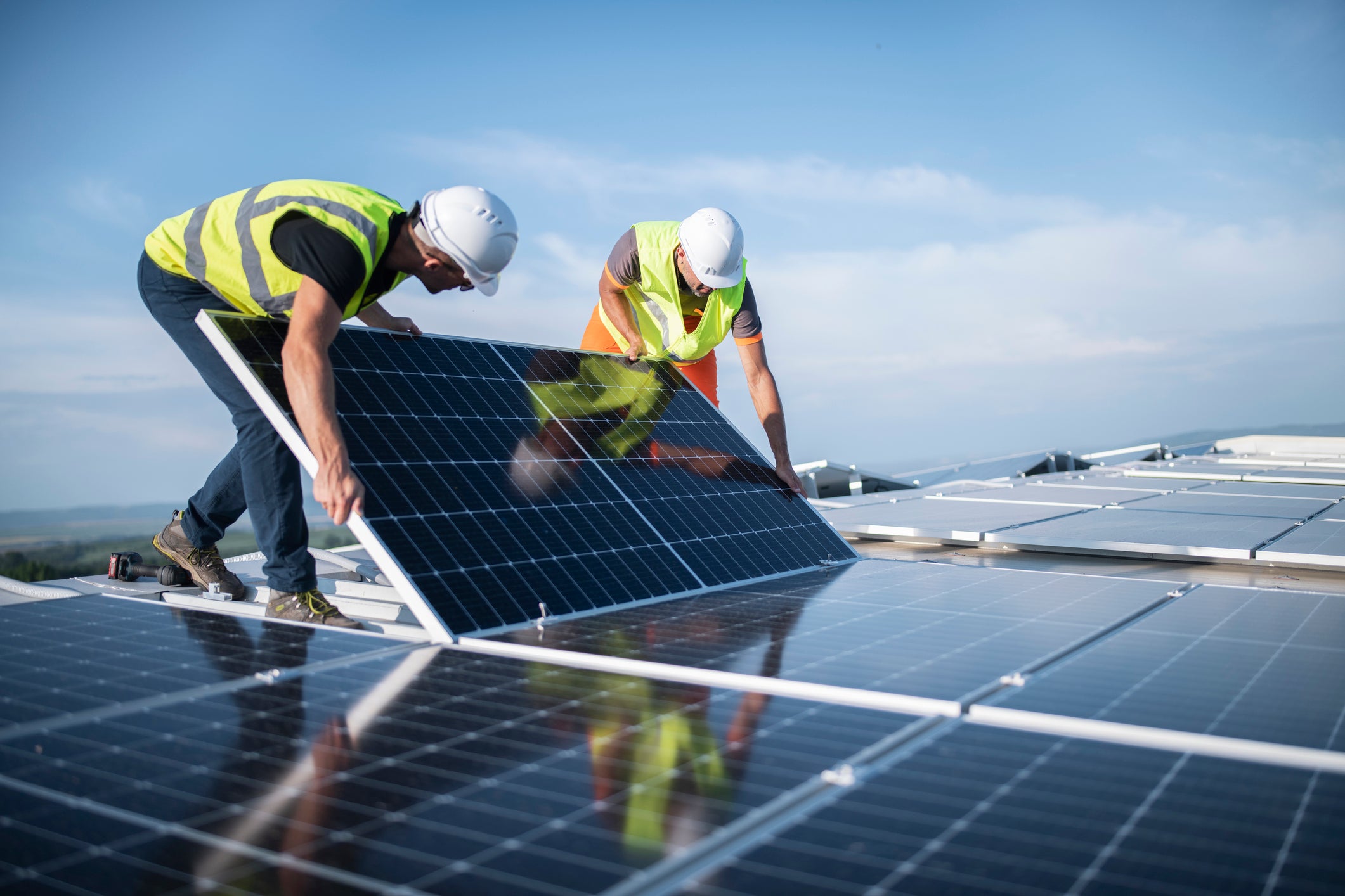 Gulf Renewable Energy Company Limited : Photo de deux travailleurs installant un panneau solaire.