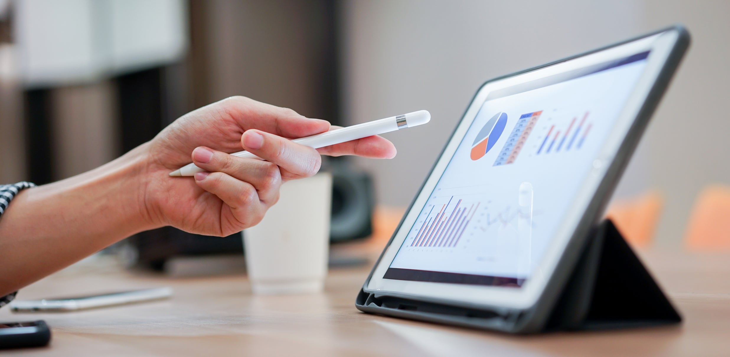Croissance du portefeuille et étapes importantes : Photo d’une main tenant un stylet pointant vers une tablette numérique affichant des graphiques. Logo de FinDev Canada en bas à gauche.