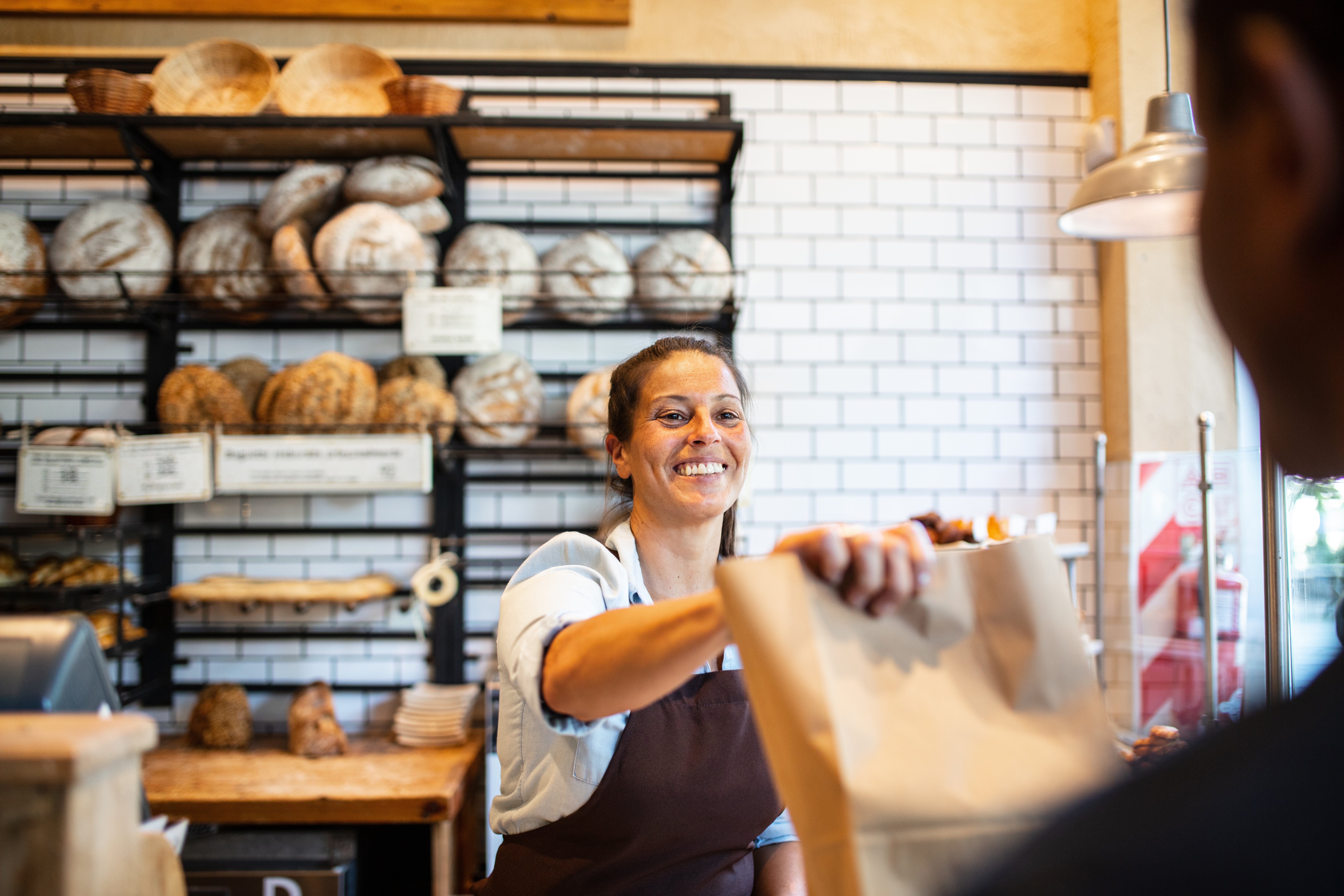 A bakery owner selling items to a customer.