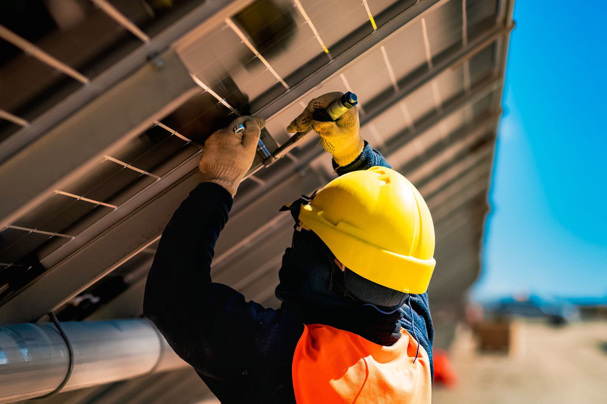 A worker is working on the back of a solar panel